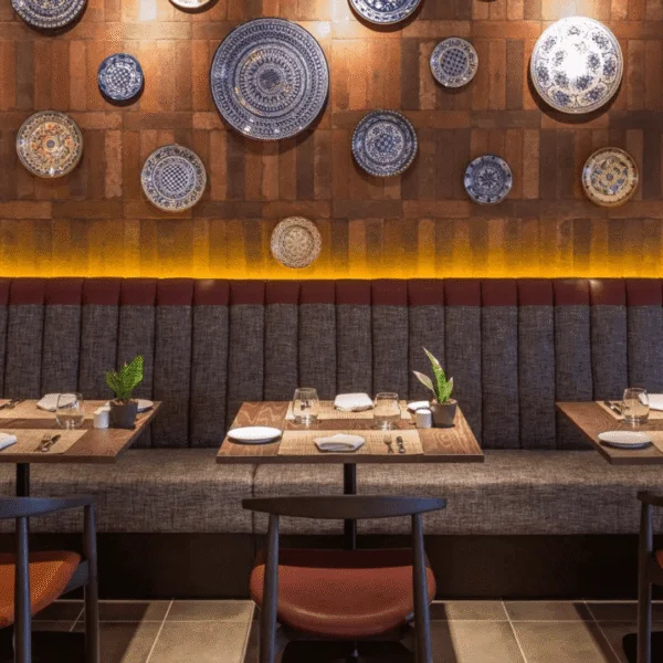 Banqueta de restaurante con respaldo tapizado y decoración de platos cerámicos.