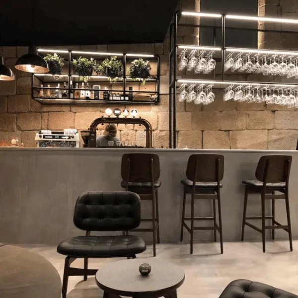 Taburetes altos y mobiliario industrial en barra de bar con iluminación cálida