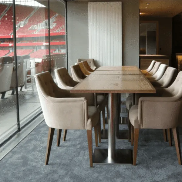 Conjunto de mesas y sillas tapizadas en palco VIP con vista al estadio.