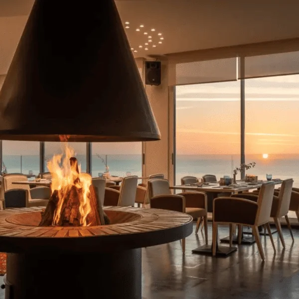 Restaurante con chimenea y vistas al mar al atardecer.