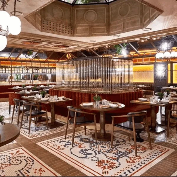 Interior de restaurante elegante con tapicería roja y mosaico tradicional en el suelo.