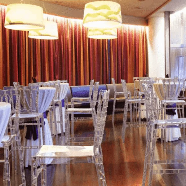 Sillas de policarbonato transparentes en comedor elegante con cortinas de colores.