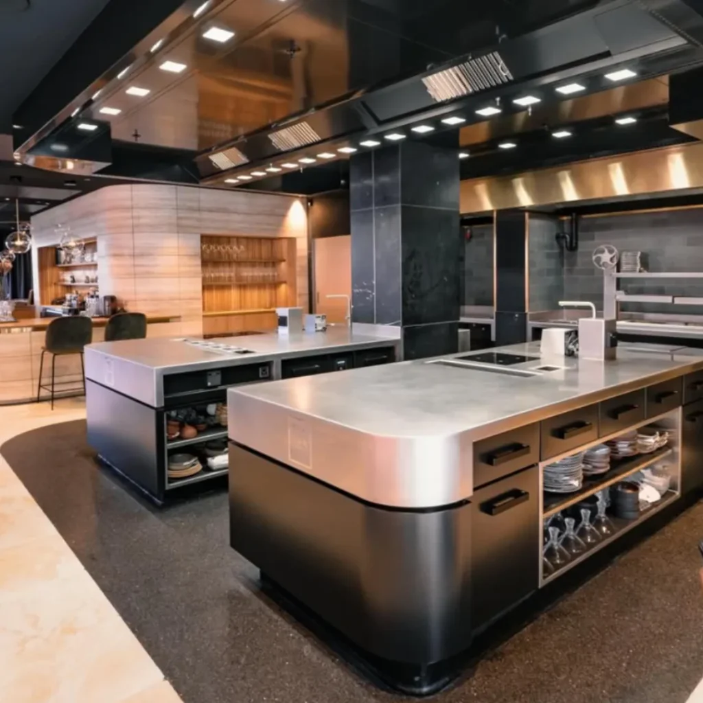 Cocina industrial negra profesional con encimeras de acero y almacenamiento visible.